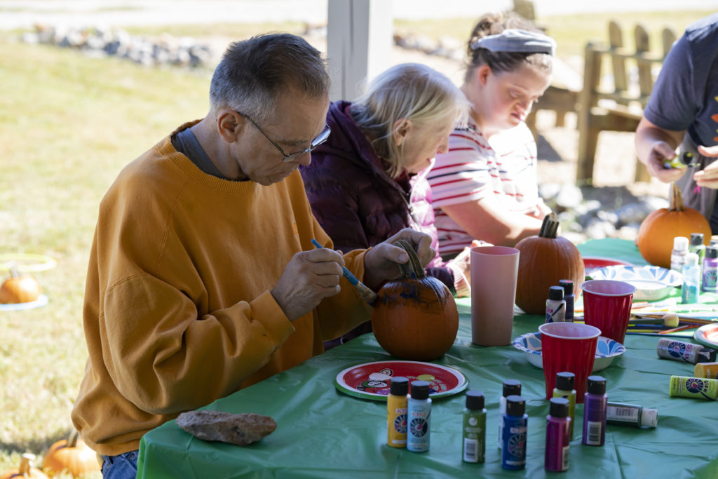 Participant painting a pumpkin during a supported creative activity